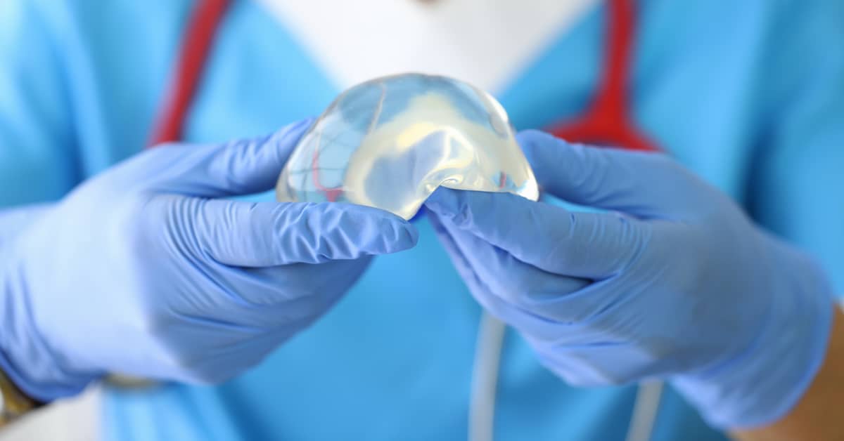 plastic surgeon holding defective silicone breast implant