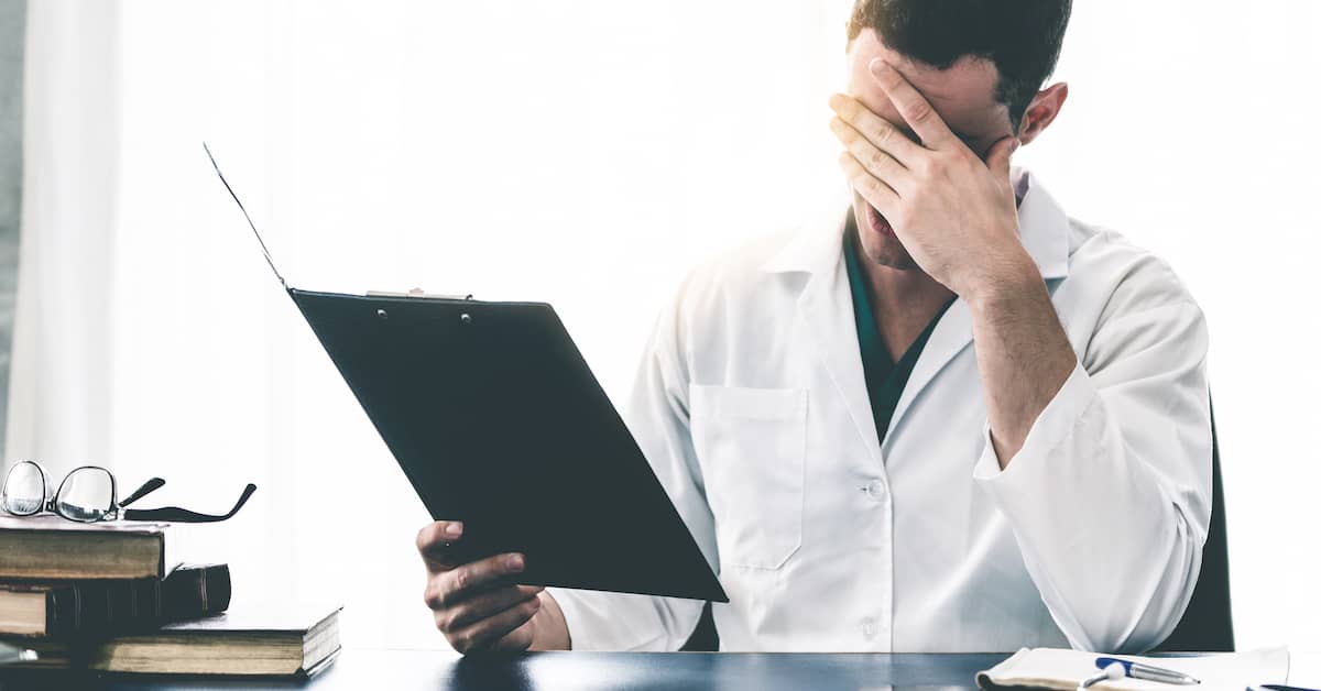 upset doctor holding clipboard with medical malpractice lawsuit