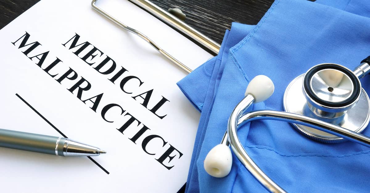 medical malpractice claim on clipboard next to surgical scrubs and stethoscope