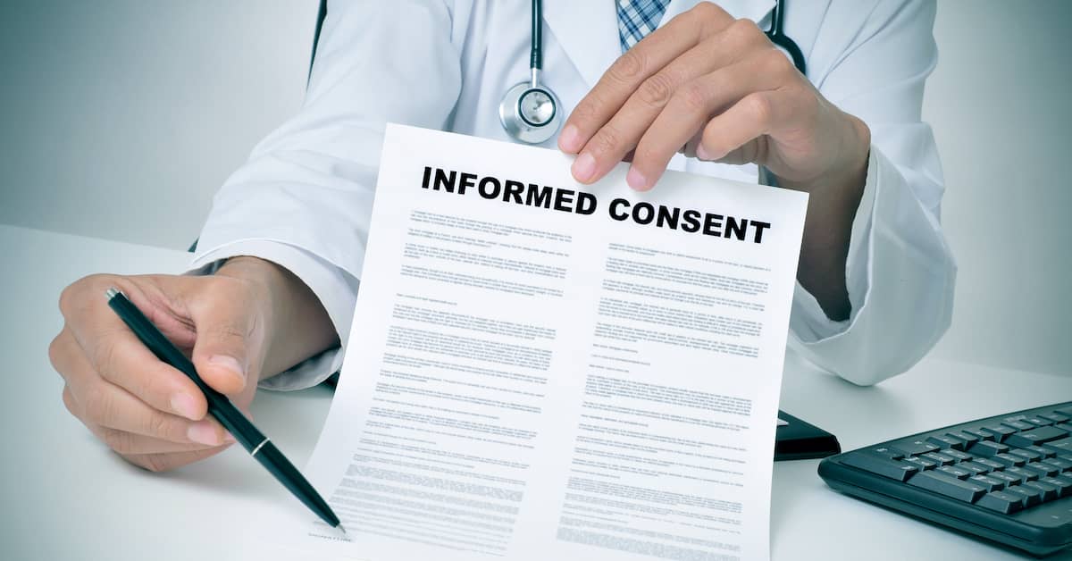 doctor holding form labelled 'Informed Consent' for patient to sign