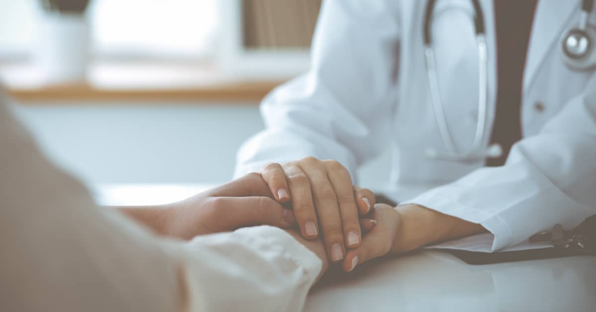 female doctor holding the hands of a distressed patient