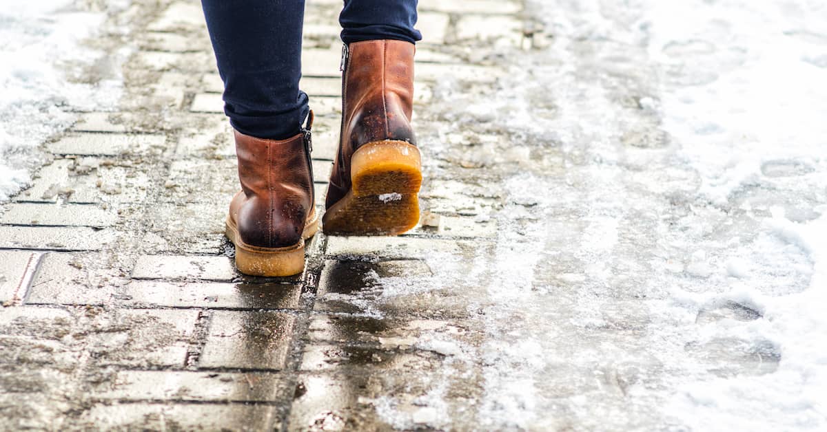 man in boots walking on icy sidewalk in the winter