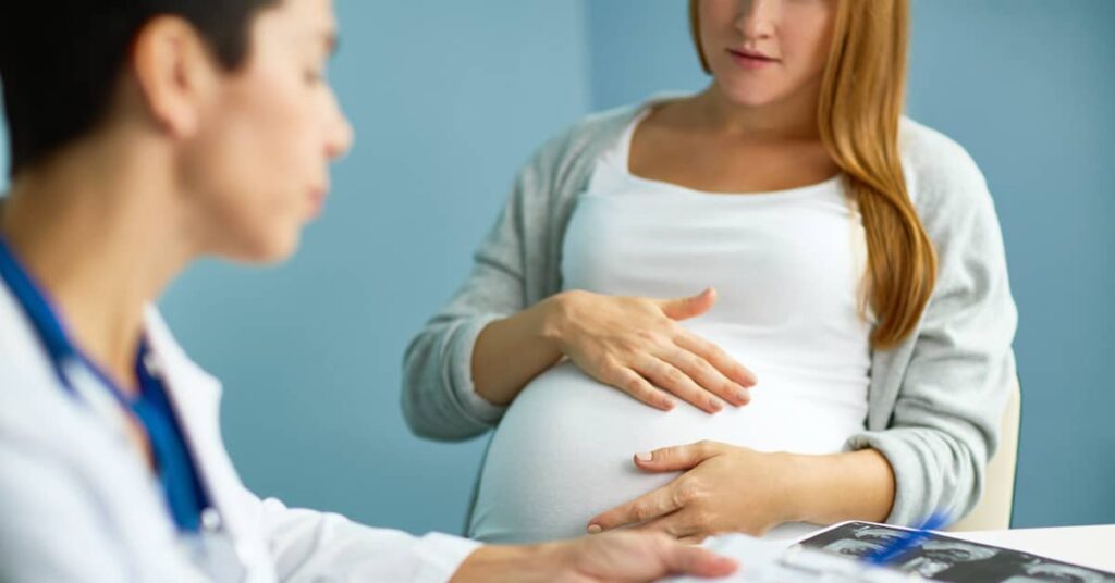 pregnant woman consulting with her OB/GYN