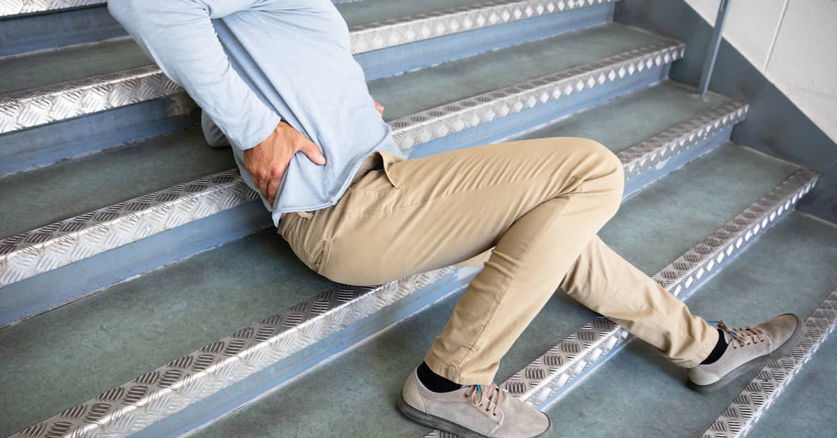 Man clutching back after slip, trip, and fall on stairs. | Klein Lawyers