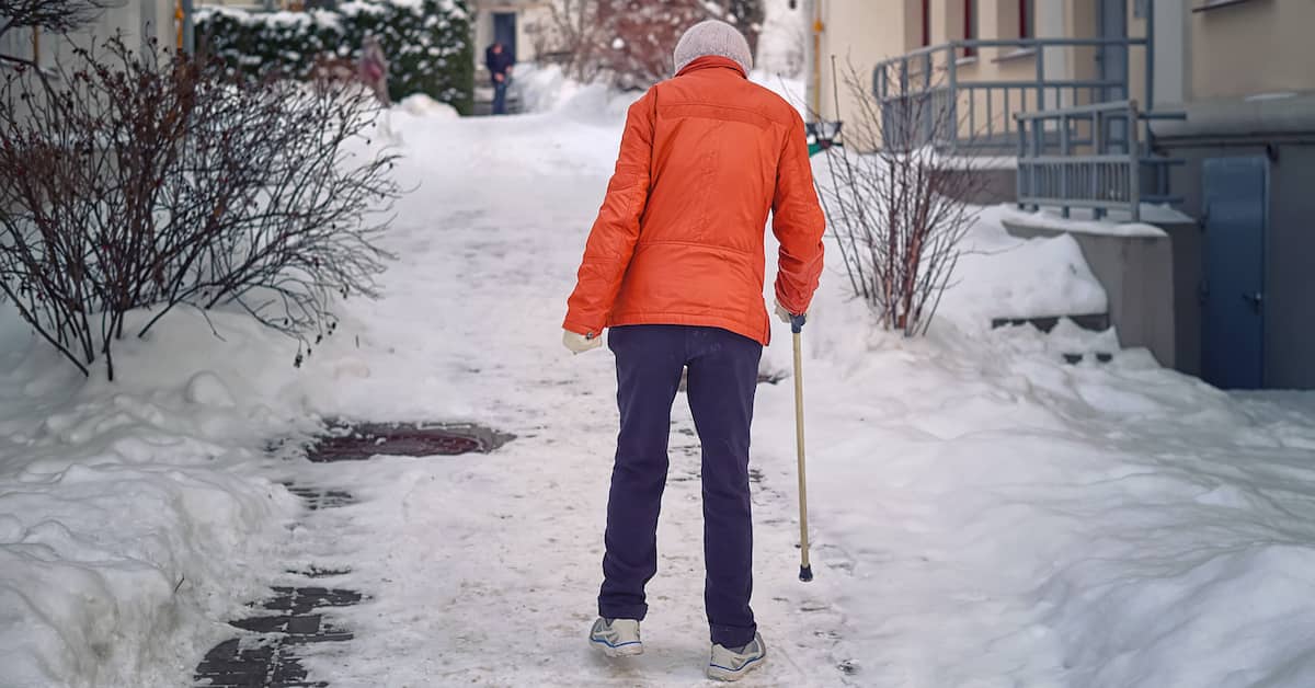 Woman with cane walks on snow and ice at a strata complex. | Klein Lawyers